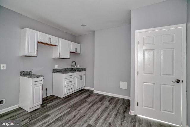 kitchen featuring dark hardwood / wood-style flooring, white cabinetry, sink, and dark stone counters