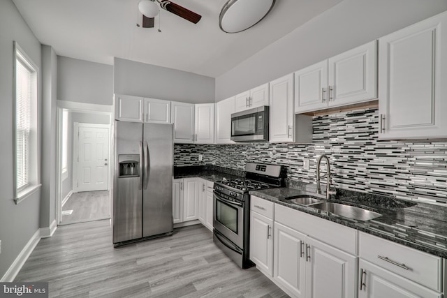 kitchen with white cabinets, stainless steel appliances, dark stone countertops, and sink