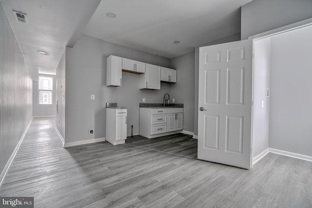 kitchen with sink, white cabinets, and light wood-type flooring