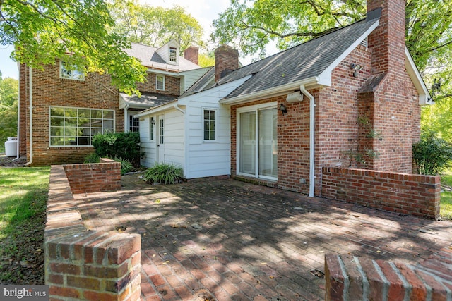 1791 Warrenton Rd, Fredericksburg, VA 22406 - back of house featuring a chimney, brick siding, a patio area, and a shingled roof