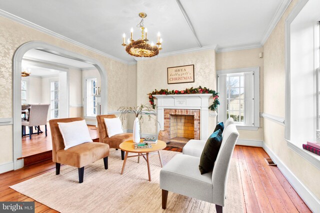 1791 Warrenton Rd, Fredericksburg, VA 22406 - living room with a chandelier, wood-type flooring, crown molding, arched walkways, and a brick fireplace