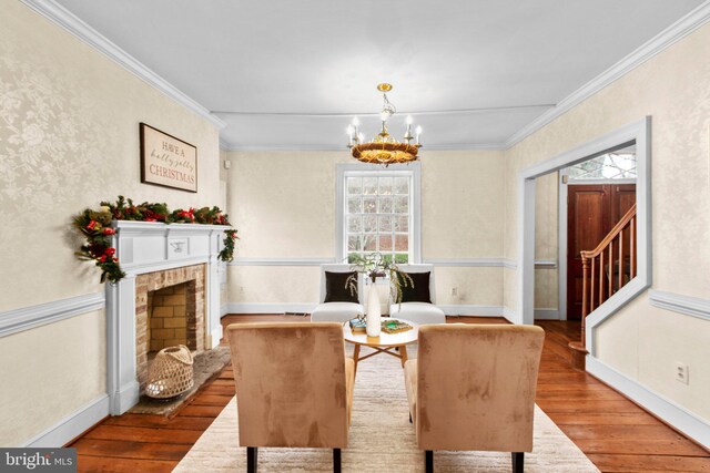 unfurnished living room with ornamental molding, a fireplace, wood-type flooring, and an inviting chandelier