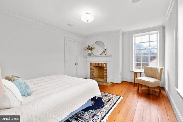 unfurnished living room featuring a brick fireplace, crown molding, and hardwood / wood-style flooring