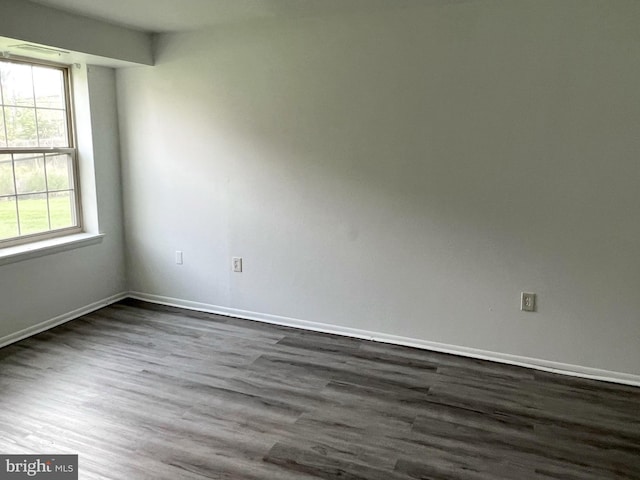 spare room with dark wood-type flooring and baseboards