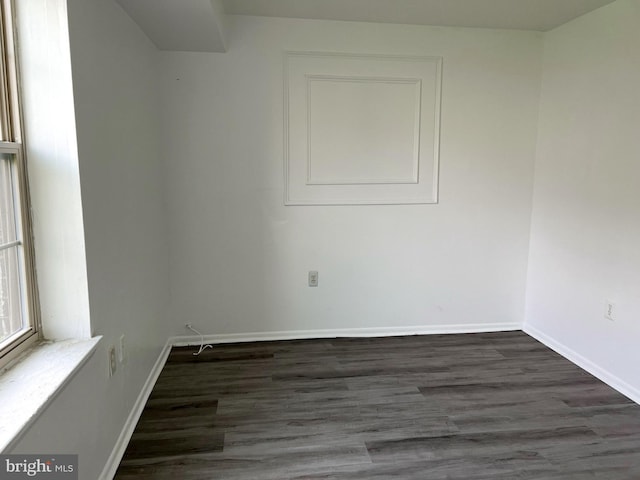 spare room featuring baseboards and dark wood finished floors