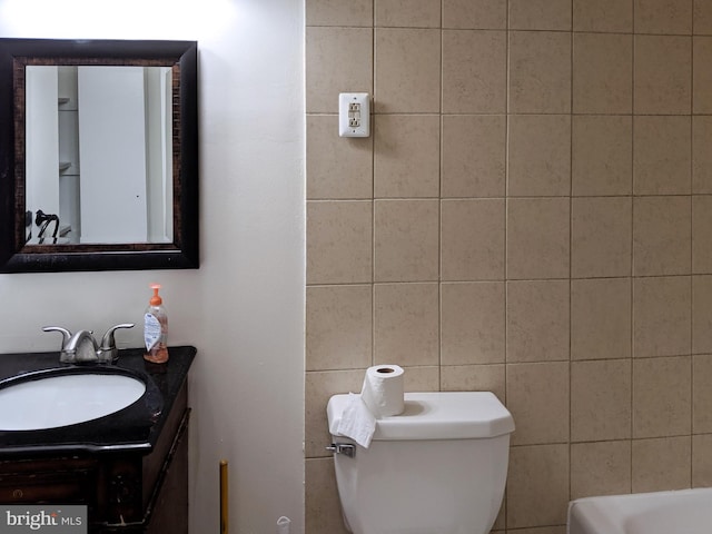 bathroom featuring toilet, tile walls, and vanity