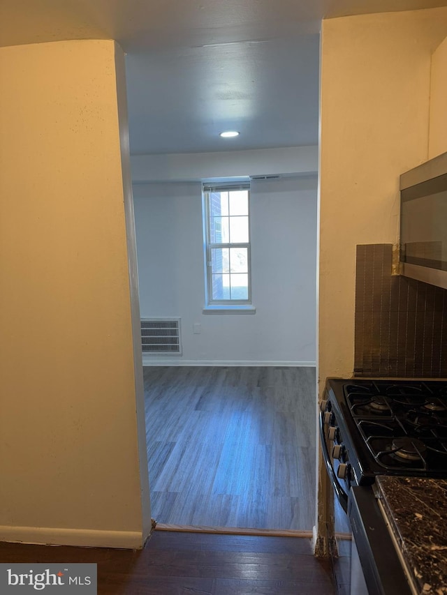 kitchen with visible vents, dark countertops, gas range, stainless steel microwave, and dark wood-style flooring