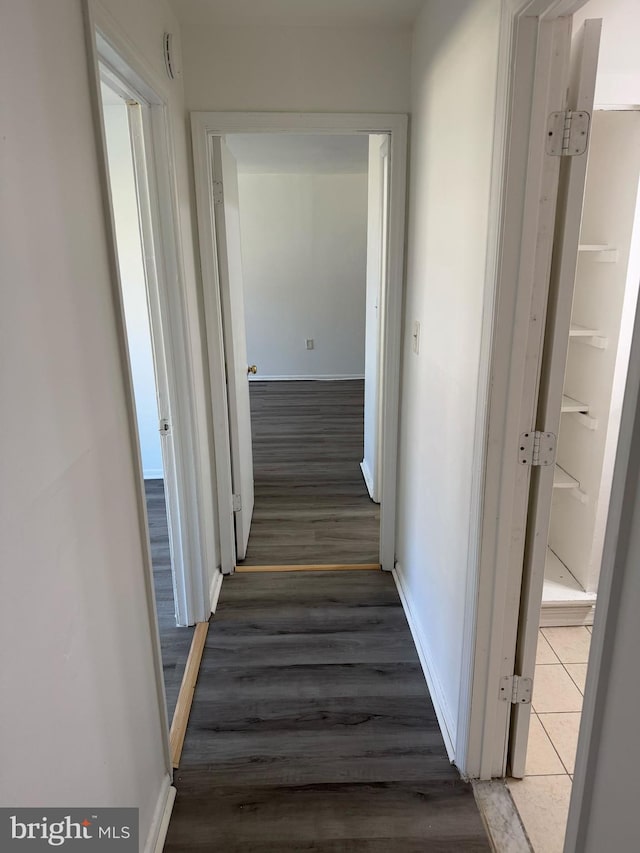 corridor with dark wood-type flooring and baseboards