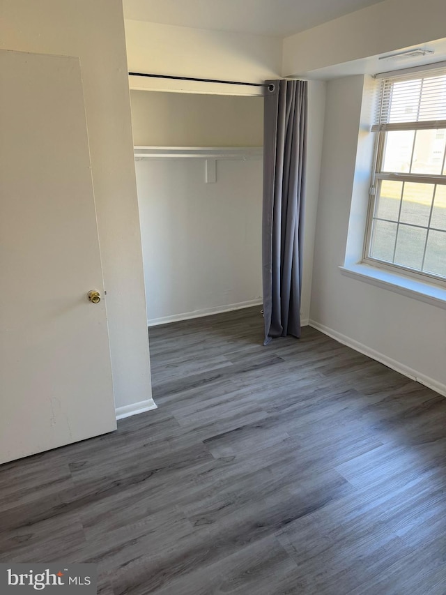 unfurnished bedroom with dark wood-type flooring, a closet, and baseboards