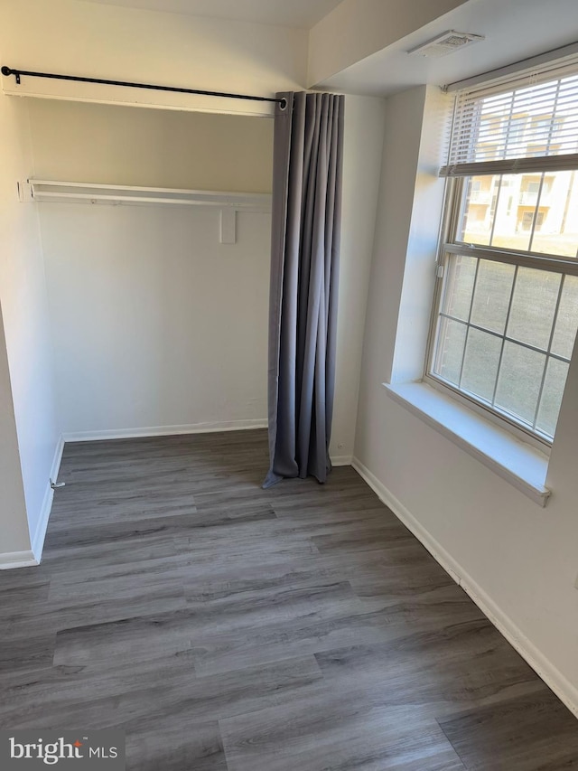 unfurnished bedroom featuring dark wood-style flooring, visible vents, and baseboards