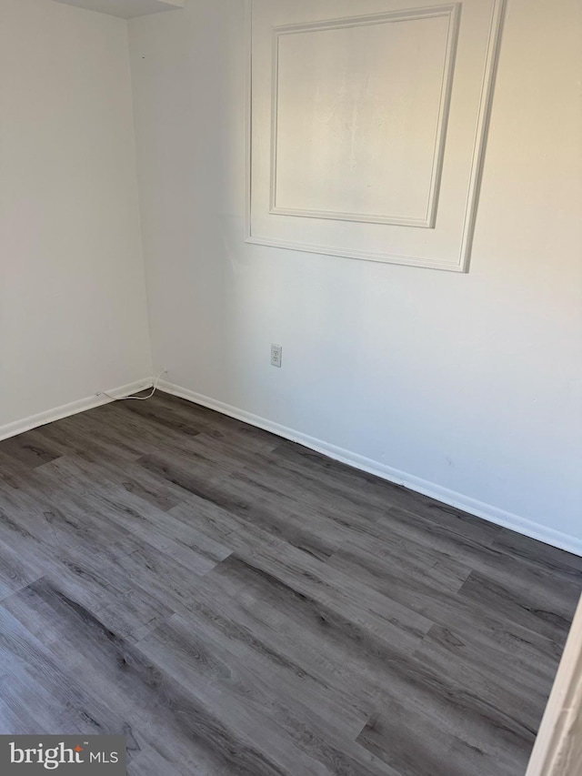 empty room featuring dark wood-style flooring and baseboards