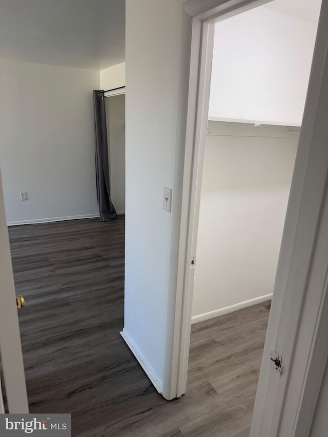 hall featuring dark wood-style floors and baseboards