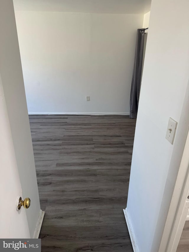 unfurnished room with dark wood-style floors and baseboards