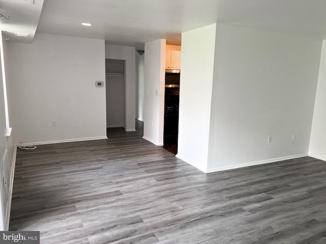 empty room featuring baseboards, dark wood finished floors, and recessed lighting