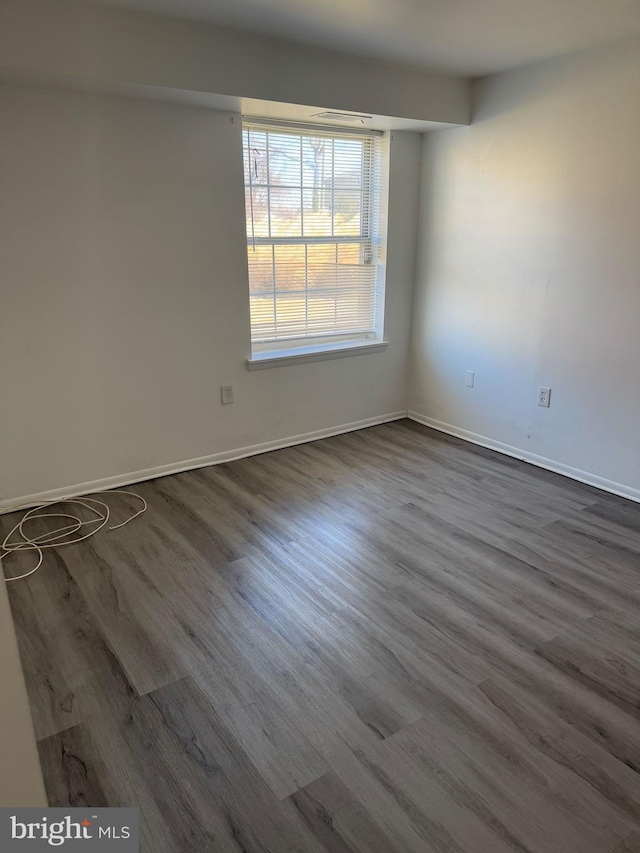 unfurnished room featuring dark wood-style floors and baseboards