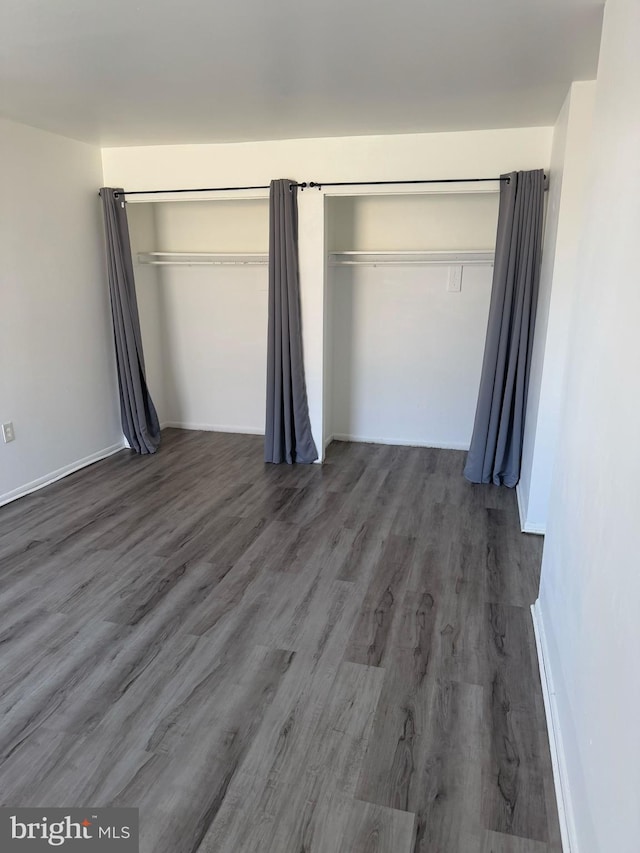 unfurnished bedroom with dark wood finished floors and baseboards