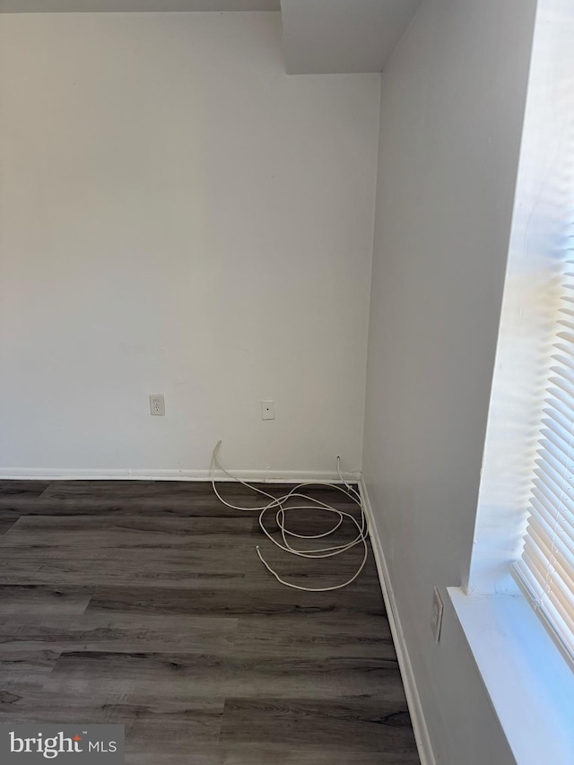 spare room with dark wood-style flooring and baseboards