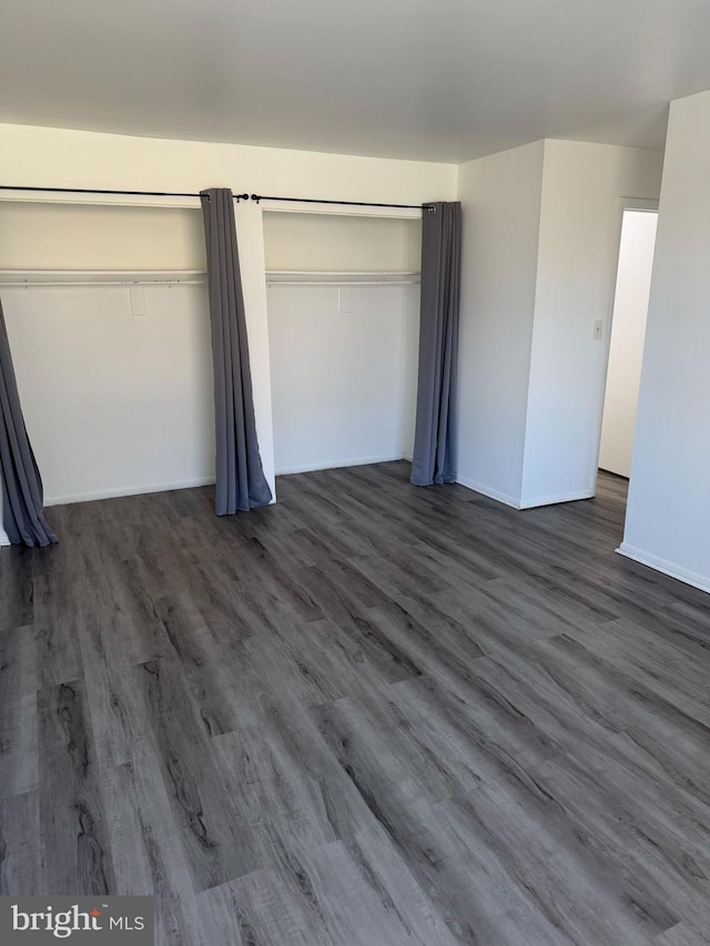 unfurnished bedroom featuring dark wood-style floors and baseboards