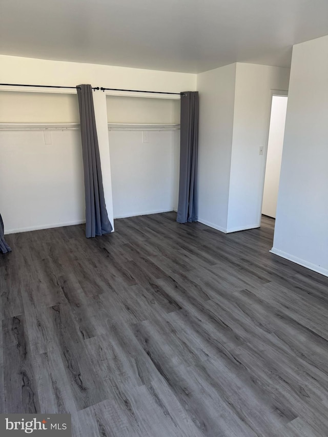 unfurnished bedroom with dark wood finished floors and baseboards