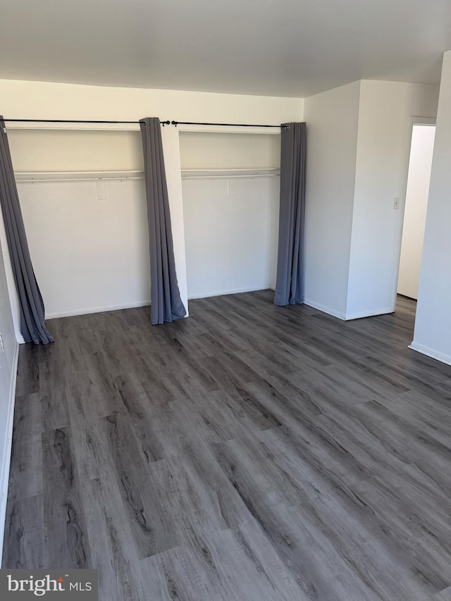 unfurnished bedroom featuring baseboards and dark wood-style flooring