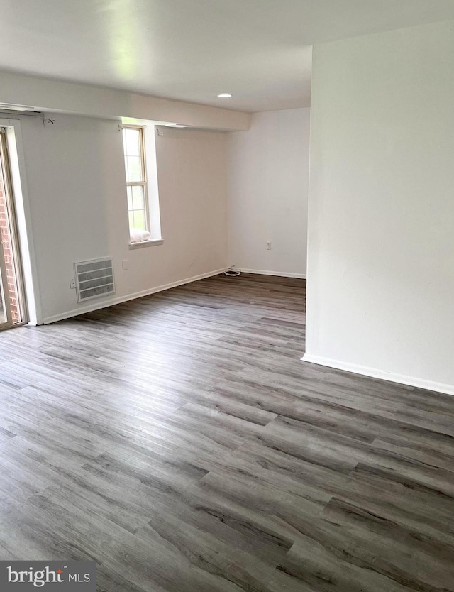 unfurnished room featuring dark wood-style floors, visible vents, and baseboards