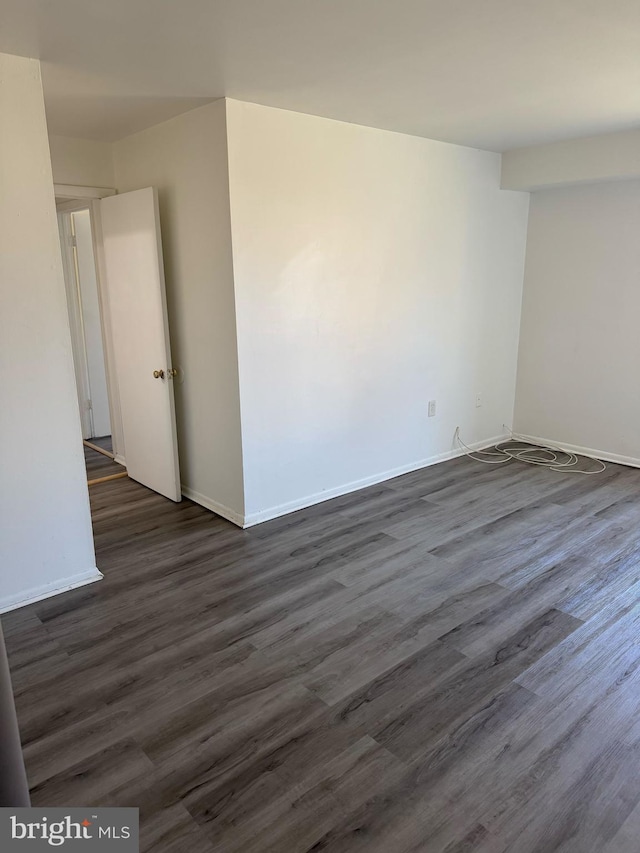 unfurnished room with dark wood-type flooring and baseboards