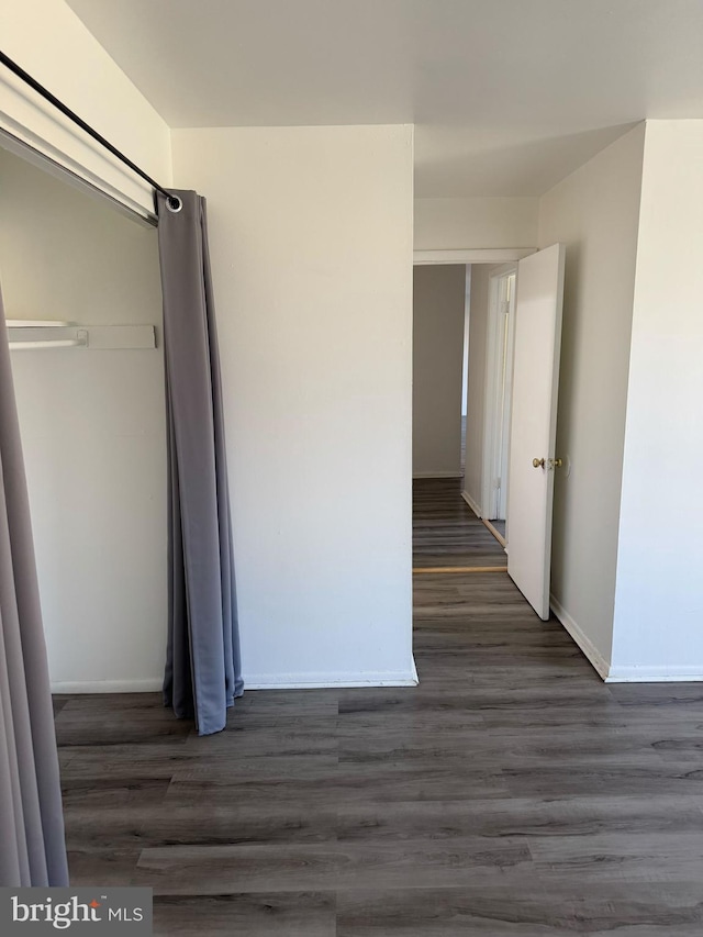 corridor featuring dark wood-style flooring and baseboards