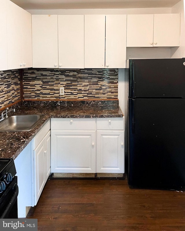 kitchen with dark wood-style flooring, a sink, white cabinetry, dark stone counters, and black appliances