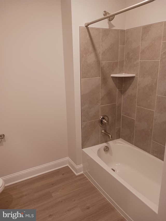 bathroom featuring hardwood / wood-style flooring, tiled shower / bath combo, and toilet