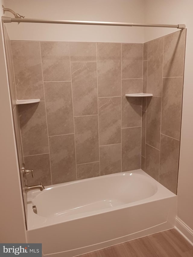 bathroom with hardwood / wood-style flooring and tiled shower / bath combo