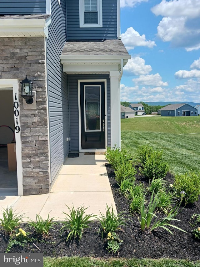 view of exterior entry featuring a lawn