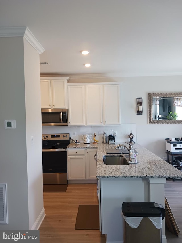 kitchen with sink, white cabinetry, light hardwood / wood-style floors, kitchen peninsula, and stainless steel appliances