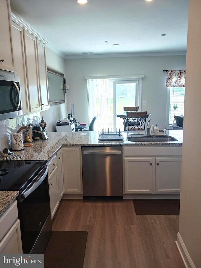 kitchen with sink, dark wood-type flooring, stainless steel appliances, light stone counters, and white cabinets