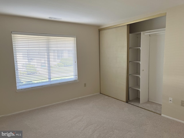 unfurnished bedroom featuring light carpet and a closet