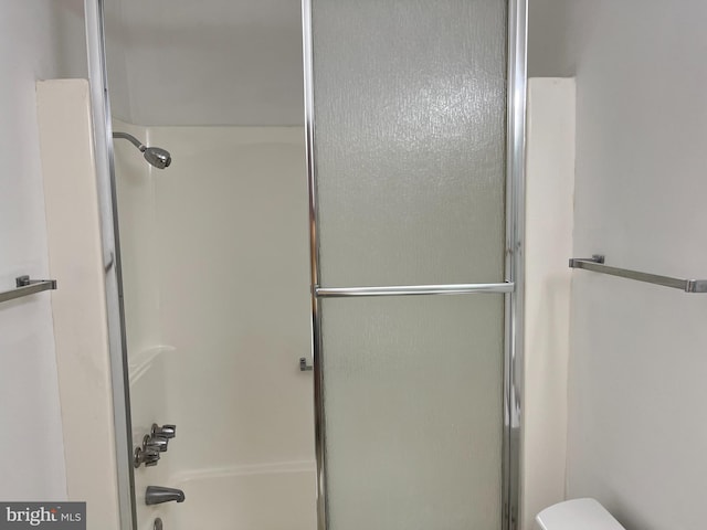 bathroom with a shower with door and toilet