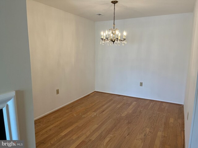 spare room with a notable chandelier and hardwood / wood-style flooring