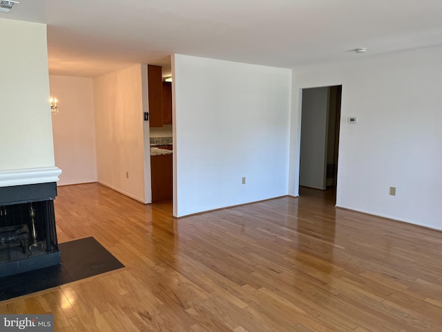 unfurnished living room featuring light hardwood / wood-style floors and a multi sided fireplace