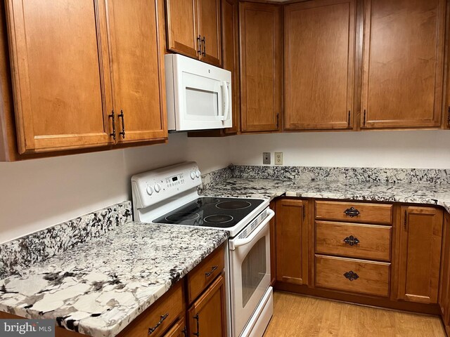 kitchen with light stone counters, light hardwood / wood-style floors, and white appliances