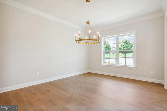 unfurnished room featuring ornamental molding, hardwood / wood-style floors, and an inviting chandelier