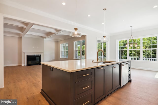 kitchen featuring coffered ceiling, a kitchen island with sink, beamed ceiling, sink, and decorative light fixtures