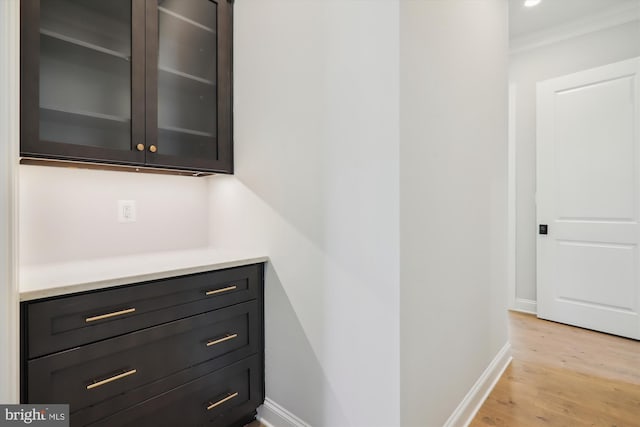 bar featuring ornamental molding and light hardwood / wood-style flooring