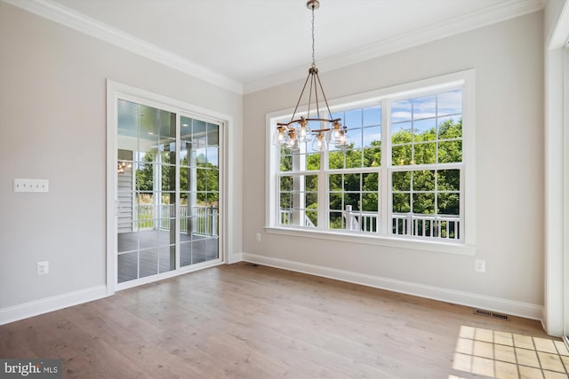 unfurnished dining area with crown molding, plenty of natural light, a notable chandelier, and light hardwood / wood-style flooring