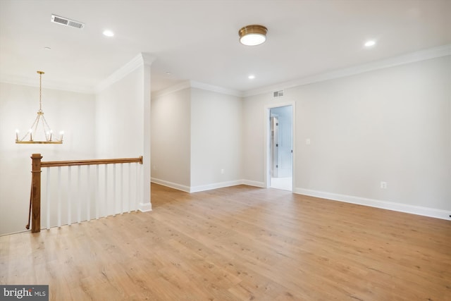 empty room featuring a notable chandelier, light hardwood / wood-style floors, and crown molding