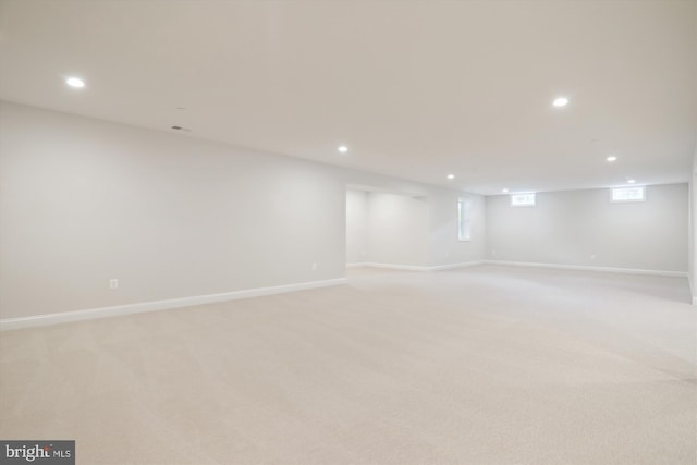 basement with a wealth of natural light and light colored carpet