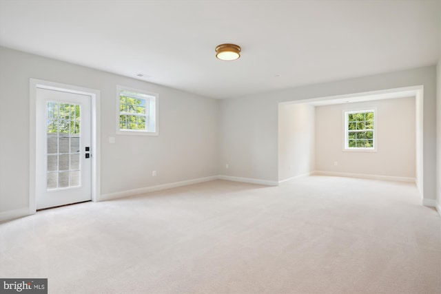 unfurnished room featuring a healthy amount of sunlight and light colored carpet