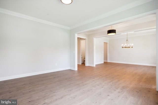 unfurnished room featuring wood-type flooring, a notable chandelier, and crown molding