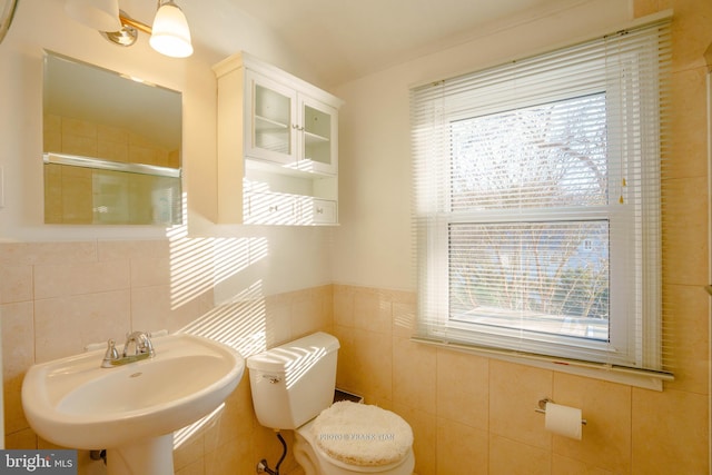 bathroom with toilet, sink, tile walls, and a wealth of natural light