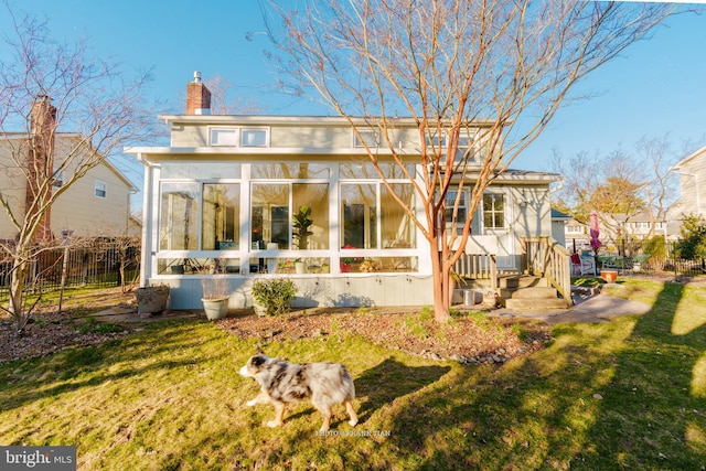 rear view of house with a lawn and a sunroom