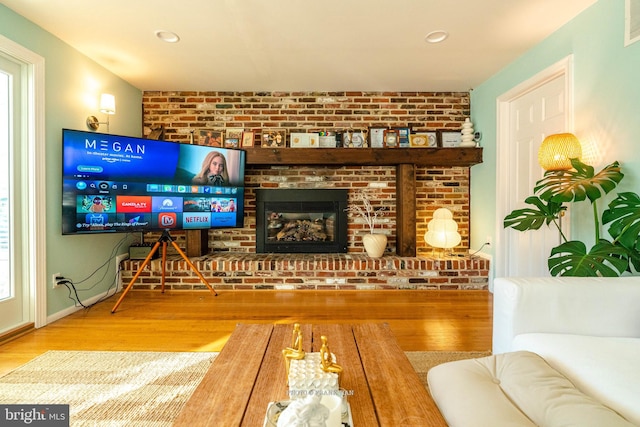 living room with wood-type flooring and a brick fireplace