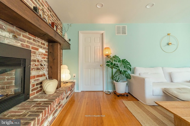 unfurnished living room with hardwood / wood-style flooring and a brick fireplace